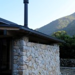 薪ストーブの煙突と石壁