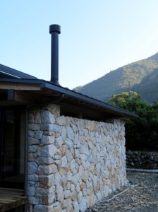 薪ストーブの煙突と石壁